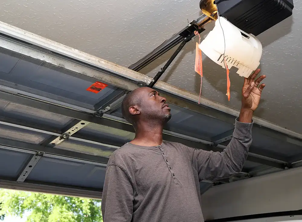 man inspecting his automatic garage door opener to see if it needs repairing